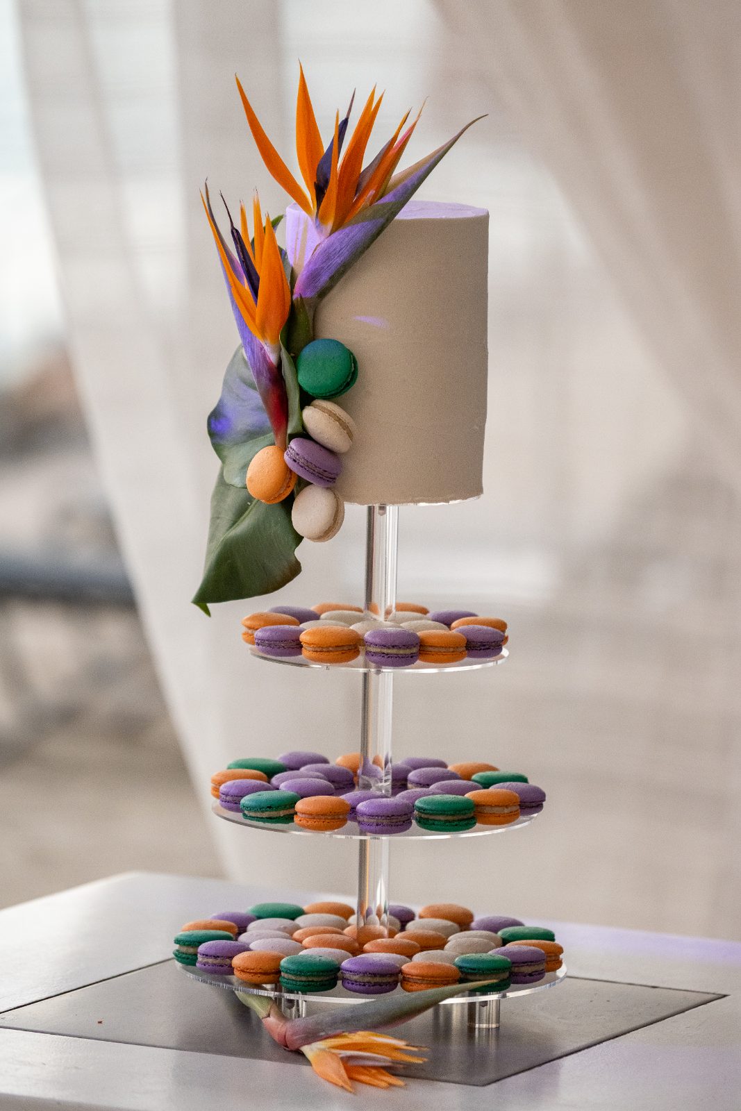 Kinga and Sven's wedding cake, featuring colorful macarons and tropical decorations, is displayed on a tiered stand at Karakter in Curaçao