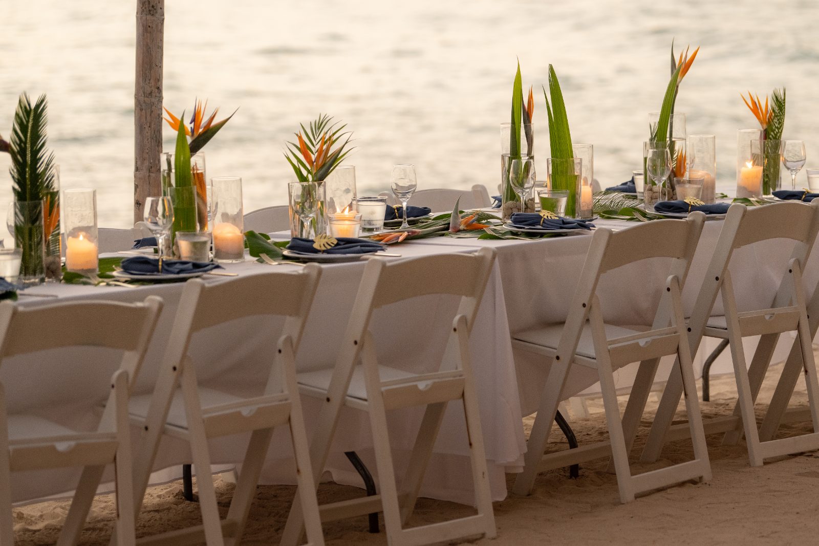 Kinga and Sven's wedding reception features a beautifully set table on the beach at Karakter, Curaçao, adorned with candles and tropical decorations