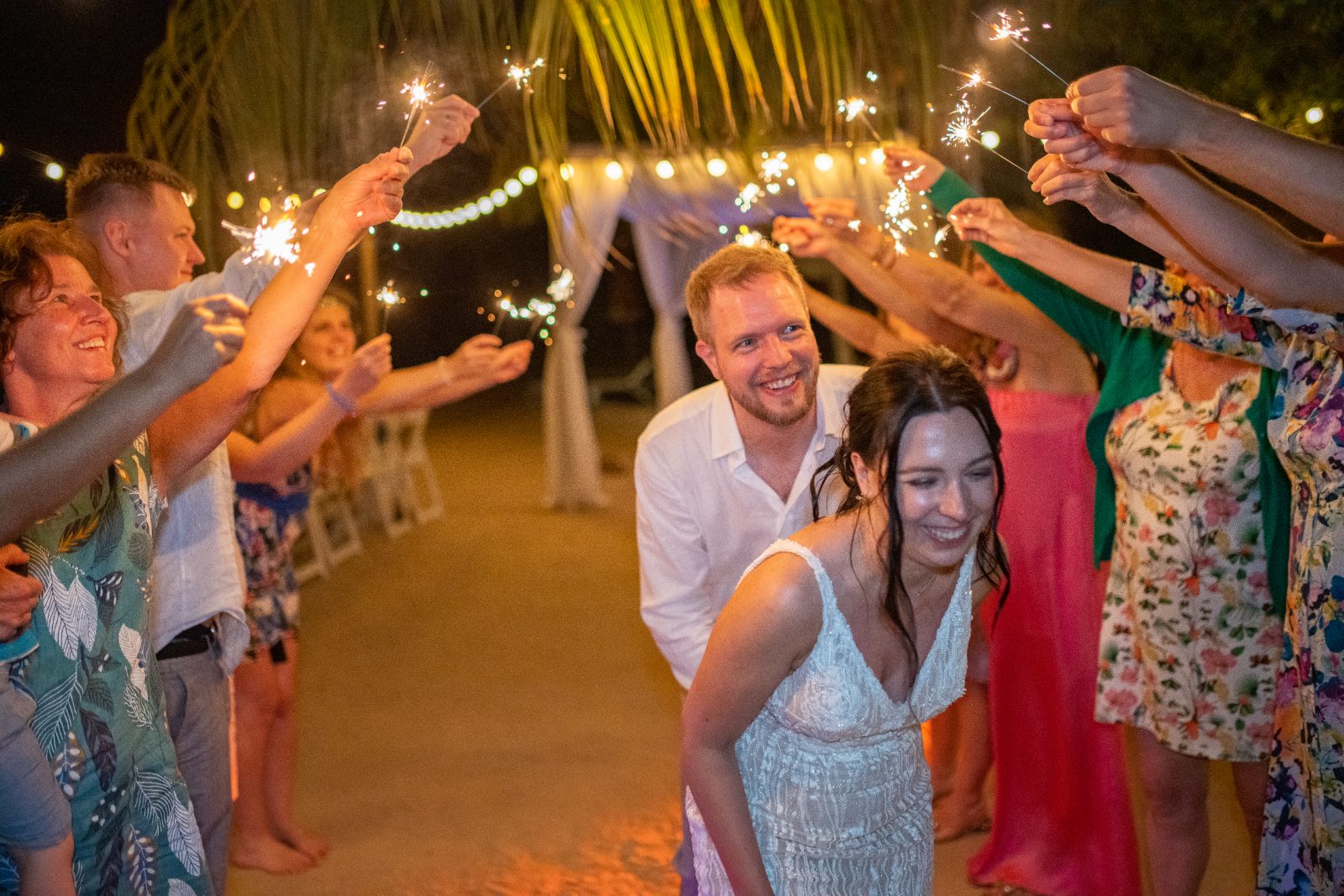 Kinga and Sven celebrate their wedding at Karakter, Curaçao, surrounded by guests holding sparklers in a festive outdoor setting