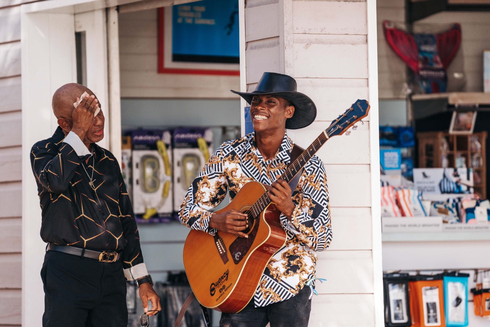 Kristal and Brittany's wedding at Karakter, Curaçao features a guitarist performing while a man stands nearby, smiling and listening
