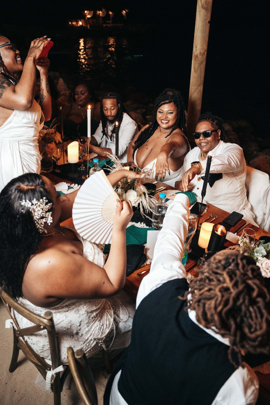 Kristal and Brittany celebrate their wedding at Karakter in Curaçao, surrounded by friends and family at a festive dinner table near the water