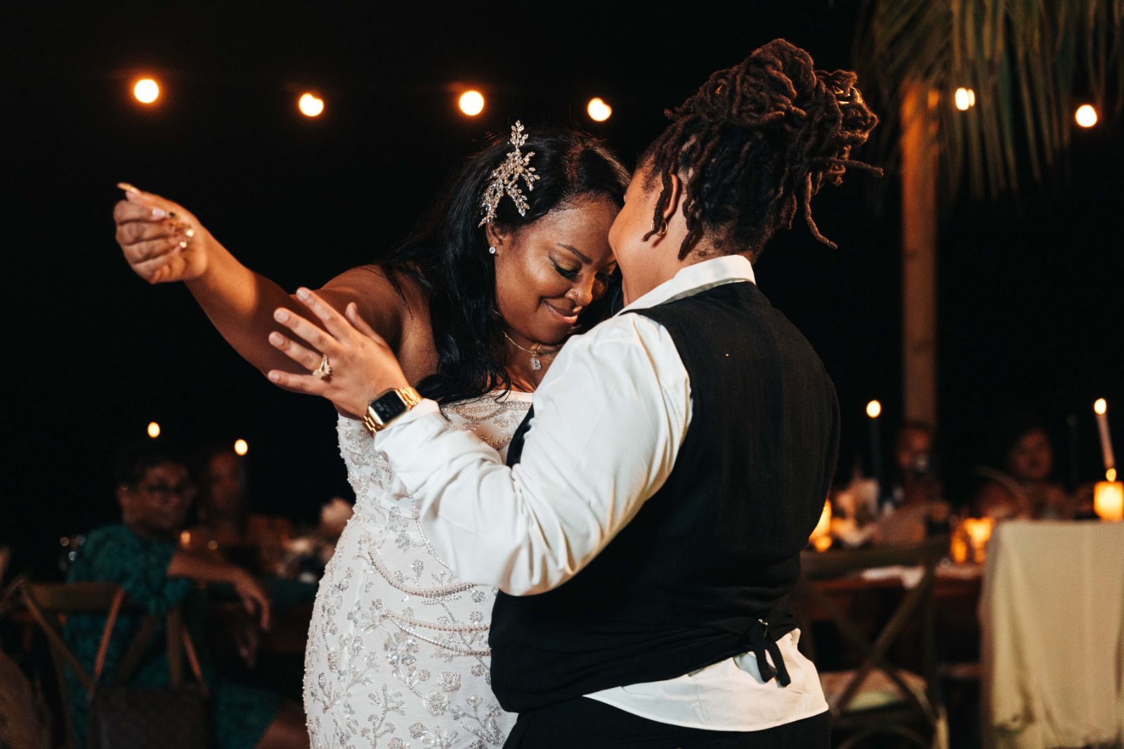 Kristal and Brittany are dancing together at their wedding reception at Karakter in Curaçao, surrounded by guests and softly lit decor