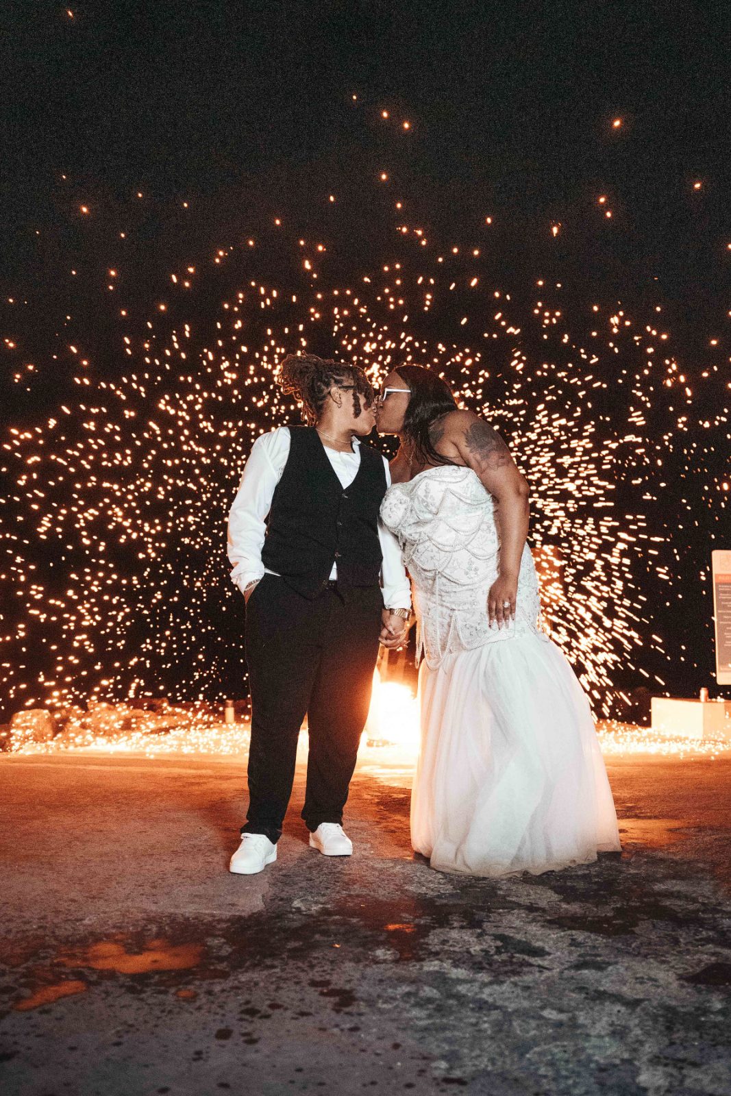Kristal and Brittany kiss in front of a backdrop of bright sparks during their wedding at Karakter, Curaçao