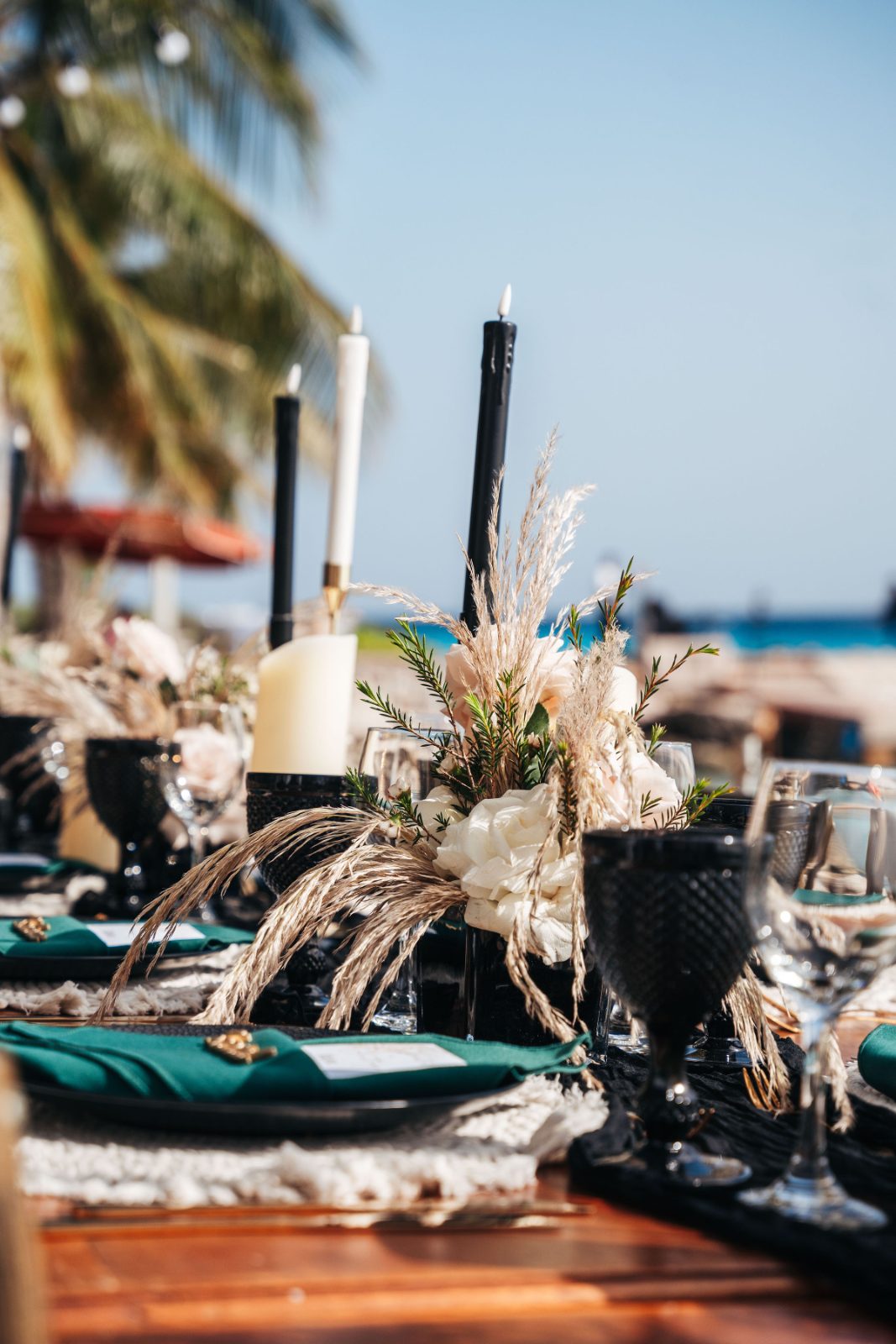 Kristal and Brittany's wedding table is set with elegant black candles and floral centerpieces, overlooking the beach at Karakter, Curaçao