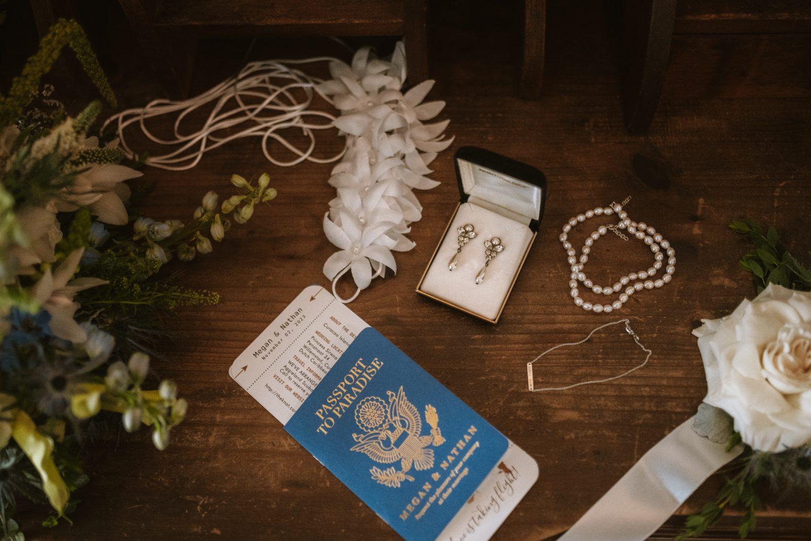 Megan and Nathan's wedding set in Curaçao features wedding accessories, including earrings, a bracelet, and a floral arrangement on a wooden surface