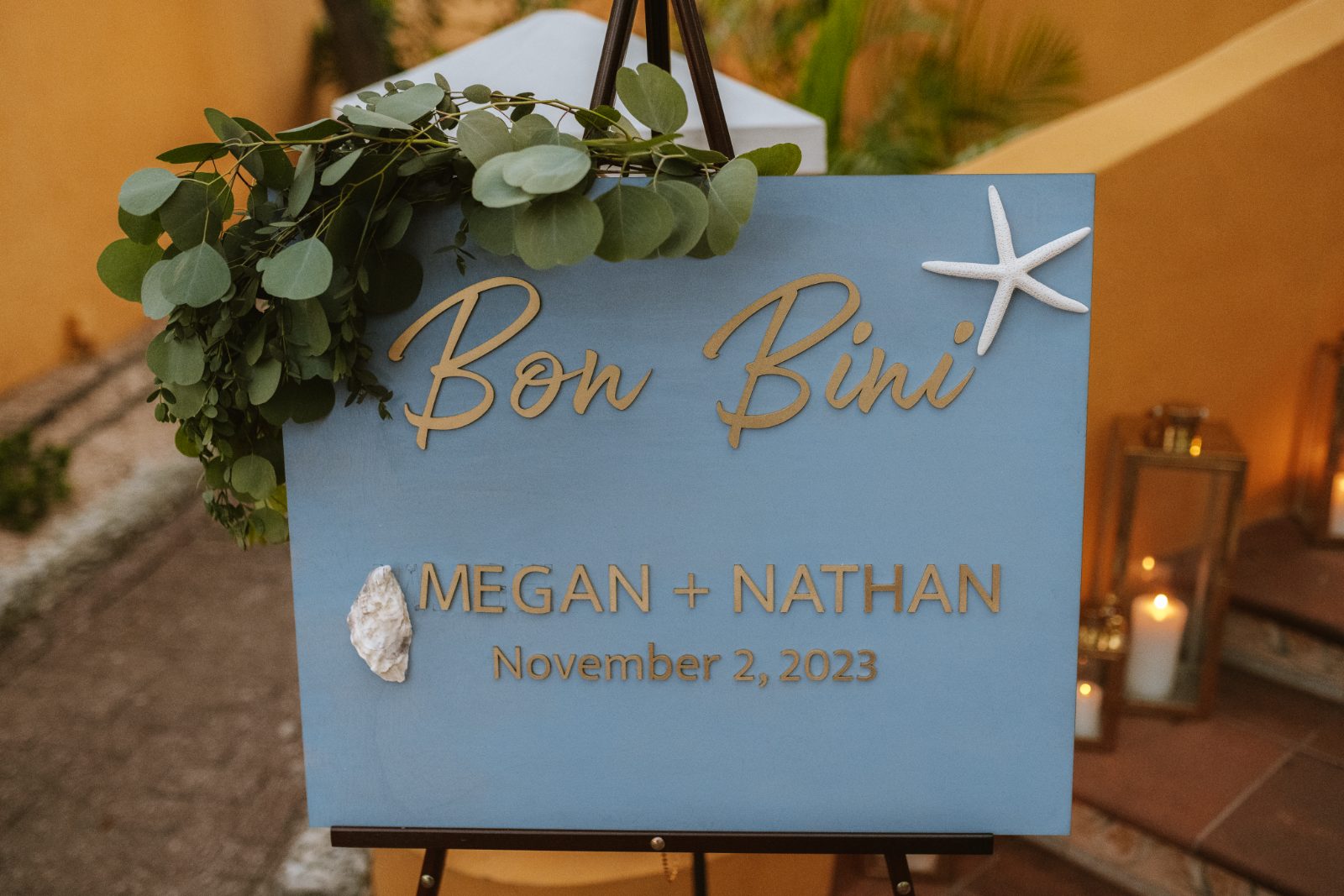 Megan and Nathan's wedding sign at Curaçao, featuring their names, date, and decorative elements including greenery and a starfish