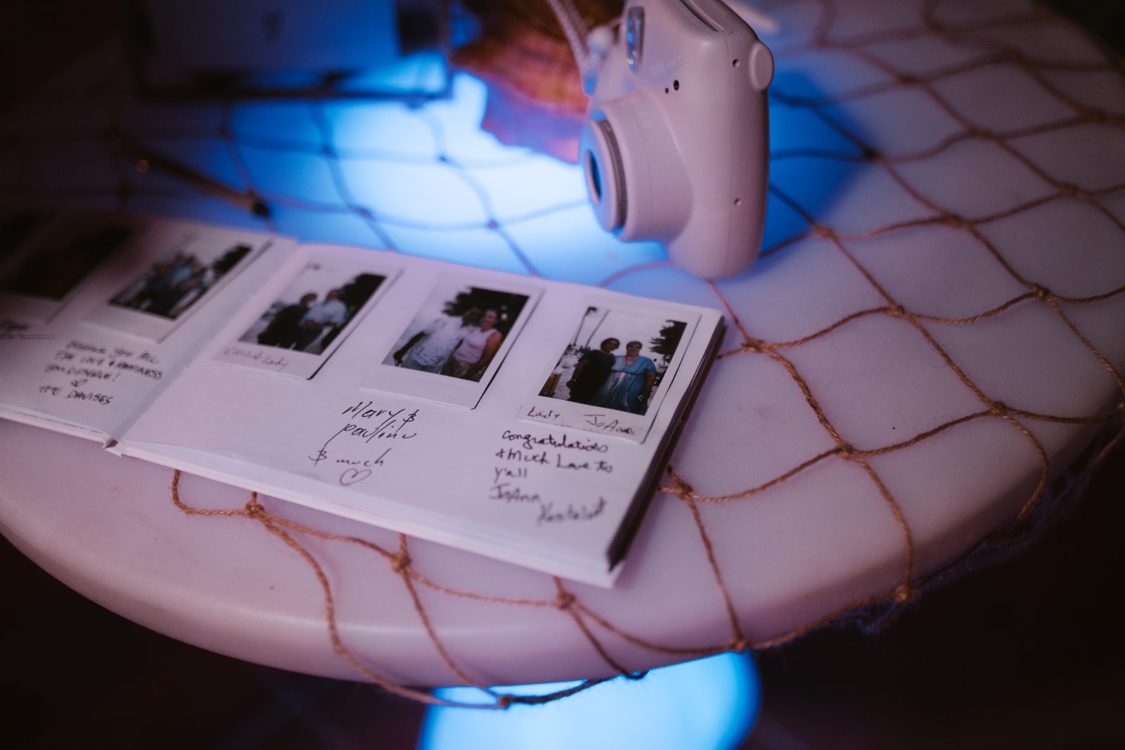 Megan and Nathan's wedding guestbook is open on a table with instant photos and messages, set in Curaçao