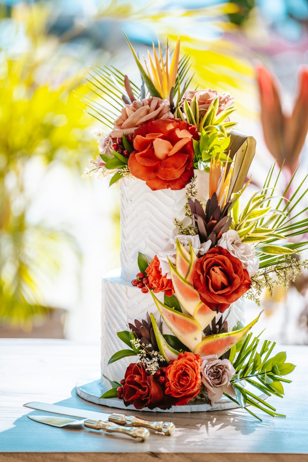Sharon and Robin's wedding cake, decorated with flowers, is displayed on a table at MOOD Beach in Curaçao