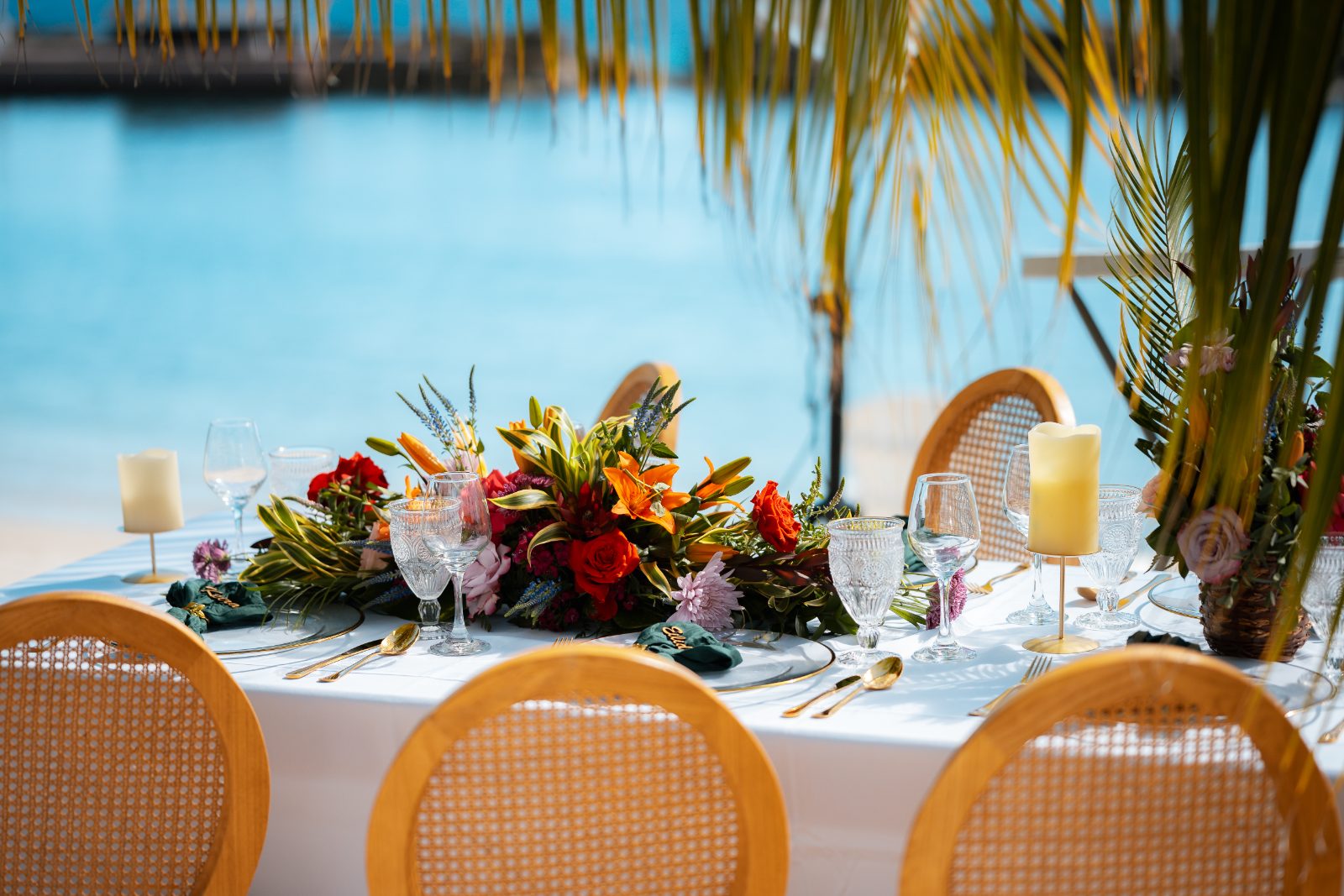 Stephanie and Simon's wedding reception features a decorated table with floral arrangements and glassware set against the backdrop of Avila Beach, Curaçao