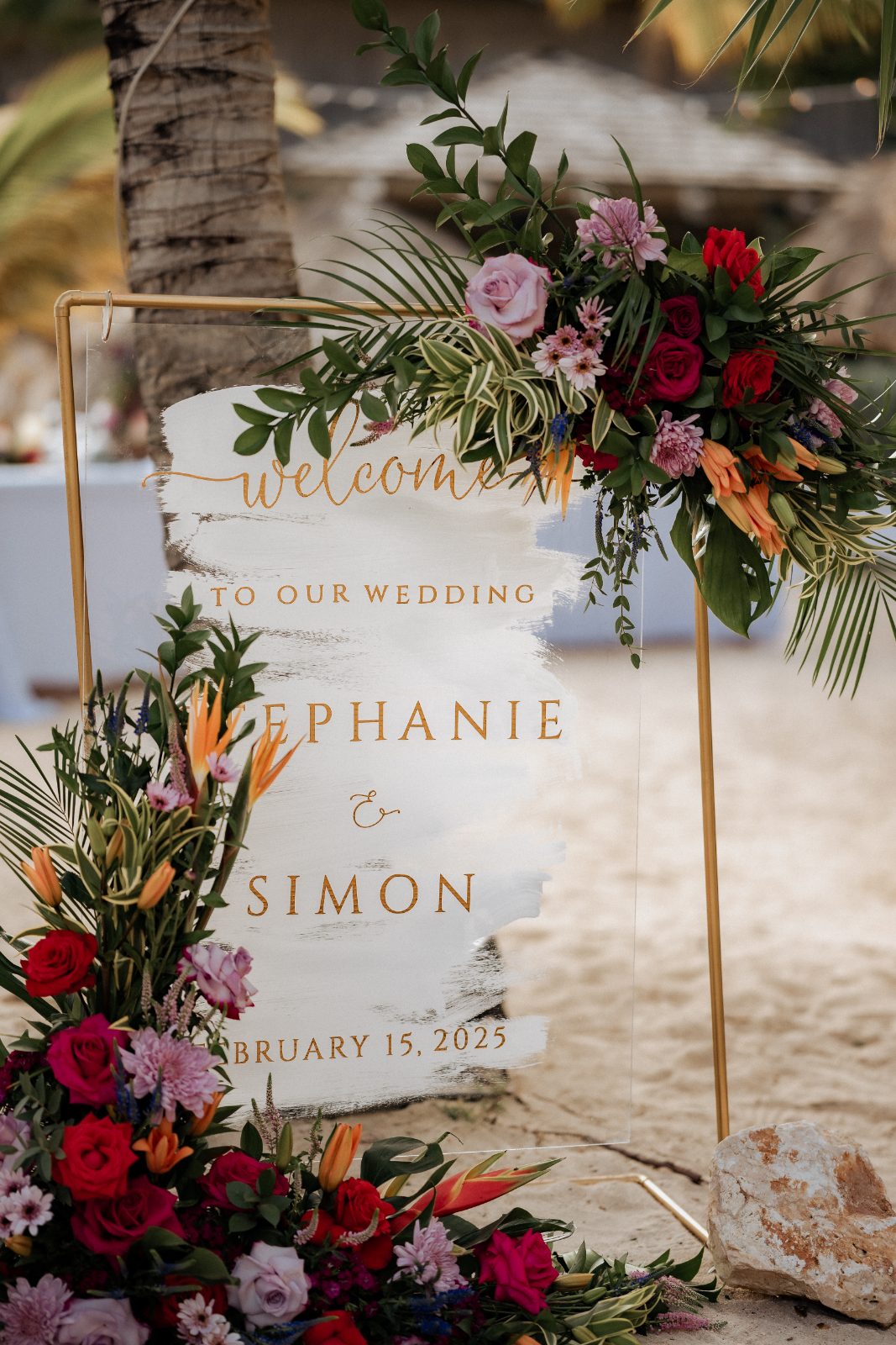 Stephanie and Simon's wedding welcome sign is decorated with colorful flowers at Avila Beach Hotel in Curaçao on February 15, 2025